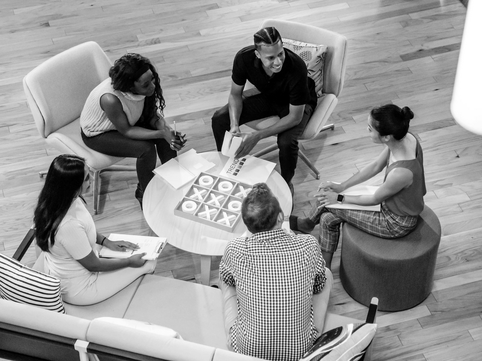 a black and white photo of a group of people sitting around a table